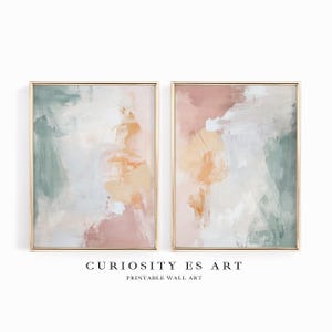 Puede incluir: Dos impresiones artísticas abstractas enmarcadas. Cada impresión presenta una mezcla de colores suaves, incluyendo rosa, verde y crema, con marcos dorados. El texto "CURIOSITY ES ART" y "PRINTABLE WALL ART" se muestra debajo.