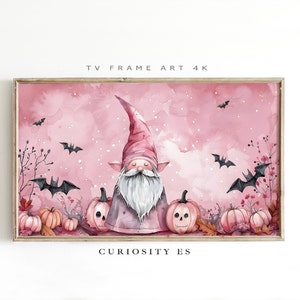 Puede incluir: Una pintura de acuarela de un gnomo rosa con barba blanca y sombrero rosa. El gnomo está rodeado de calabazas rosas con caras espeluznantes. El fondo es una acuarela rosa con murciélagos volando. El texto "CURIOSITY ES" está en la parte inferior de la imagen.