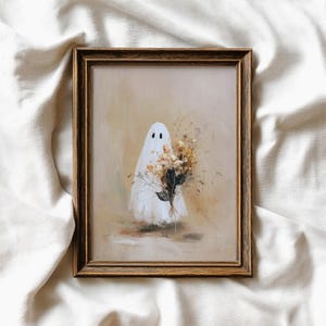 Puede incluir: Una obra de arte enmarcada que presenta un fantasma caprichoso sosteniendo un ramo de flores secas. El fantasma está envuelto en una sábana blanca con dos agujeros negros para los ojos. La obra de arte tiene una paleta de colores suaves y apagados con una estética vintage.