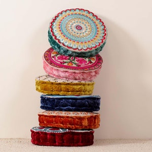 May include: A stack of six round, colourful floor cushions with various patterns. The cushions are made of velvet and have a variety of colours, including teal, pink, yellow, blue, orange, and red.