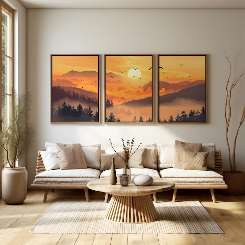 Puede incluir: Tres impresiones art&iacute;sticas enmarcadas que representan una puesta de sol sobre una cordillera con &aacute;rboles silueteados y p&aacute;jaros volando. La obra de arte presenta tonos c&aacute;lidos anaranjados y marrones, con un marco de madera.