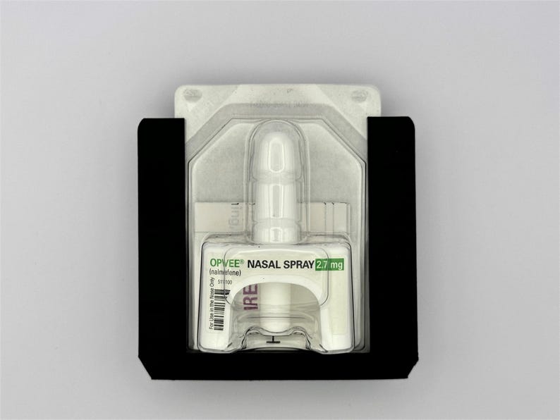 May include: A white nasal spray bottle with a clear plastic cap, labeled "OPVEE&reg; NASAL SPRAY 2.7 mg (intranasal)". The bottle is packaged in a black plastic holder.