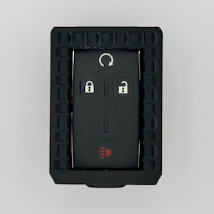 May include: Black key fob with a rubberised case. The fob has buttons for lock, unlock, boot release, and panic.