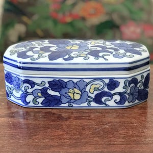 Caixa de joias retangular de cerâmica com decoração de flor azul.