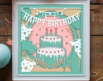 May include: A paper cut-out card with a teal background and a pink circle in the center. The circle has a white cake with red dots and white frosting, three lit candles, and the words "Happy Birthday" in a white banner.
