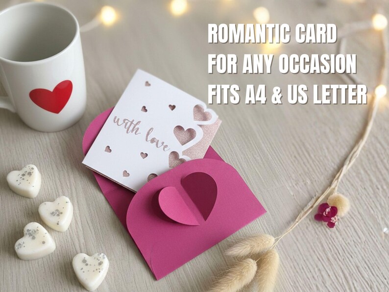 Pu&ograve; includere: Una tazza bianca con un cuore rosso, un biglietto rosa con ritagli a forma di cuore e una busta abbinata. Il biglietto recita "with love" e viene visualizzato il testo "ROMANTIC CARD FOR ANY OCCASION FITS A4 & US LETTER".