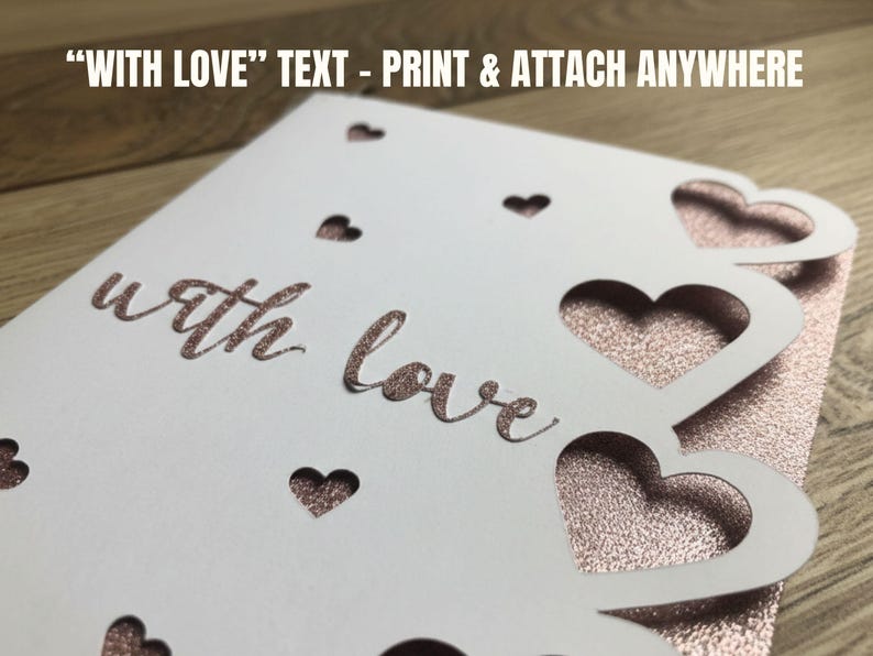Pu&ograve; includere: Un biglietto bianco con ritagli a forma di cuore e le parole "with love" in un carattere oro rosa glitterato. Il biglietto ha un retro glitterato oro rosa. Il testo "WITH LOVE" - PRINT & ATTACH ANYWHERE &egrave; in alto.