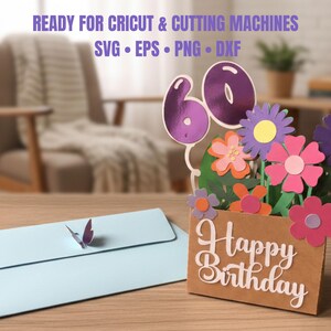 May include: A handmade birthday card with a floral design and the number 60. The card is brown with the words "Happy Birthday" in white script. A light blue envelope with a butterfly is in the foreground. Text at the top says "READY FOR CRICUT & CUTTING MACHINES".