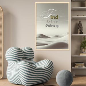 Può includere: Una stampa incorniciata con sfondo bianco e un paesaggio desertico. Il testo "Find joy in the ordinary" è scritto in lettere dorate.