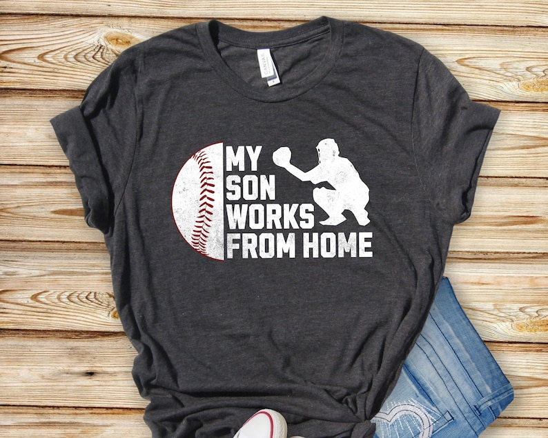 May include: A dark grey t-shirt with a white baseball graphic and the text "My son works from home".