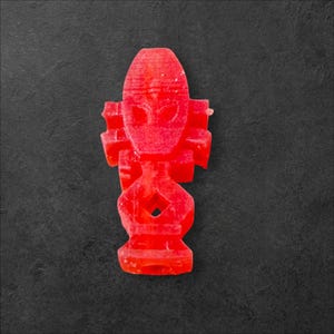 May include: A red, abstract, geometric, 3D printed figurine. The figurine is shaped like a person with a large head and a small body.