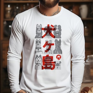 Puede incluir: Camiseta blanca de manga larga con un gráfico de varias razas de perros y texto japonés en rojo. El diseño presenta varias ilustraciones de perros y caracteres japoneses. La camiseta está hecha de un material suave.