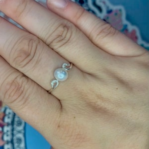 May include: A silver ring with a single white pearl set in a delicate design.