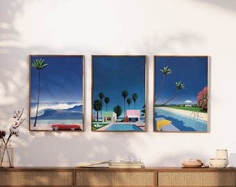 May include: Three framed prints with a retro 80s aesthetic. The prints feature a blue sky, palm trees, and a beach scene. One print shows a red convertible car driving on the beach, another shows a house with a pool, and the third shows a pool with a yellow towel.