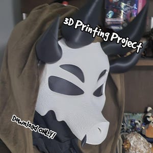 May include: A white, textured, animal-like mask with large, dark, curved horns and dark eye cutouts. The mask is worn with a brown hooded garment. Text on the image reads 3D Printing Project and DOWNLOAD ONLY! in a white, stylized font.