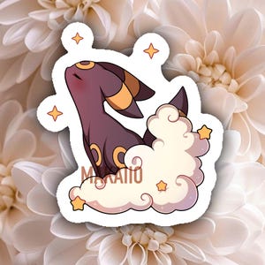 Peut inclure: Un autocollant représentant une créature violette avec des détails jaunes, émergeant d'un nuage. L'autocollant a une bordure blanche et est orné d'étoiles. Le texte "Mokaito" est en bas.