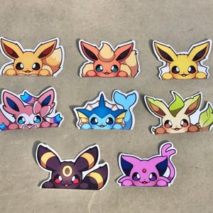 May include: A collection of eight die-cut stickers featuring colorful cartoon creatures. The set includes various characters with distinct features like large ears, tails, and vibrant color palettes including yellow, orange, pink, blue, green, and purple.