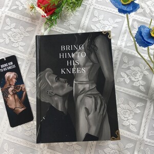 May include: A book and bookmark with a grayscale illustration. The book cover reads "BRING HIM TO HIS KNEES" with an image of a person kneeling before another. The bookmark features a similar illustration and text.