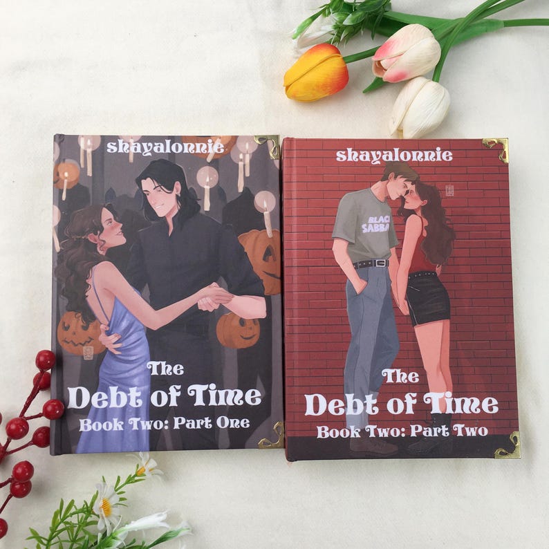 May include: Two books titled "The Debt of Time" are displayed. The first book, "Book Two: Part One," features a couple dancing in front of a Halloween-themed background. The second book, "Book Two: Part Two," shows a couple kissing in front of a brick wall.