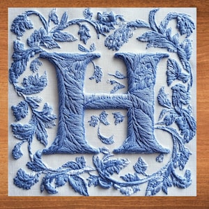 May include: A blue embroidered letter H surrounded by a floral design on a white background.