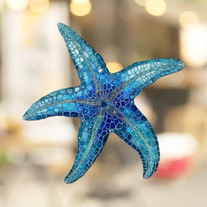 May include: A blue and teal mosaic starfish with a detailed design. The starfish is made of small, individual pieces of glass or tile.
