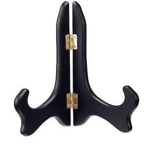 May include: A black wooden display stand with a curved design. The stand has two hinged sections connected by brass-colored hinges. The base features a curved support for holding items.