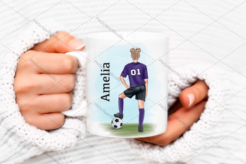 May include: White ceramic mug with a blue background and a cartoon illustration of a girl wearing a purple soccer uniform and holding a soccer ball. The text "Amelia" is written in black on the left side of the mug and the number "01" is on the girl's jersey.