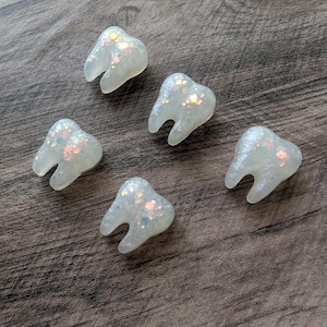Op de afbeelding: Een set van drie keramische mokken met een gespikkelde, matte afwerking. De mokken zijn in crème, lichtgrijs en donkergrijs. Elke mok heeft een eenvoudig, minimalistisch ontwerp.