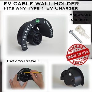 K&ouml;nnte beinhalten: Ein schwarzer Wandhalter aus Kunststoff f&uuml;r ein EV-Ladekabel. Der Halter tr&auml;gt die Aufschrift "EV Charger" und "Cable Here". Der Halter ist an einer Wand montiert und auch auf wei&szlig;em Hintergrund abgebildet. Der Text "Made in USA" ist auf einem roten Kreis gedruckt.