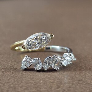 Anello aperto con diamante a taglio marquise bicolore, diamante sintetico di forma mista, fascia avvolgente in oro 14 carati.