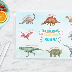 May include: A blue and white placemat with colorful illustrations of different dinosaurs. The placemat features the text "Let the world hear you roar!" and the names of each dinosaur.