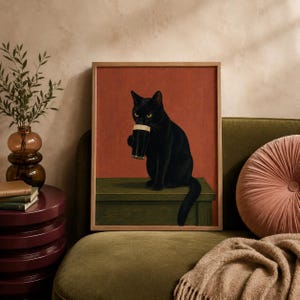 Könnte beinhalten: Ein gerahmter Kunstdruck, der eine schwarze Katze zeigt, die auf einem grünen Tisch vor einem einfarbigen terrakottafarbenen Hintergrund sitzt. Die Katze hält ein dunkles Glas Stout-Bier mit einer cremeweißen Schaumkrone.