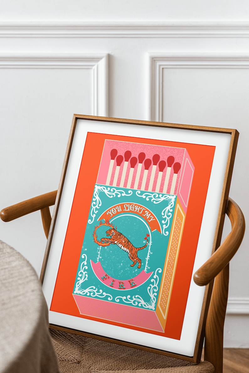 May include: A framed print with a red background featuring a matchbox with a tiger illustration and the text "You light my fire".