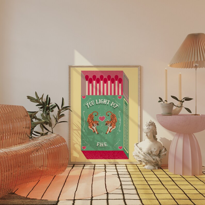 May include: A framed print of a vintage matchbox with a green background and the text "You Light My Fire". Two tigers are facing each other with a heart between them. The matchbox is surrounded by a red and white border.