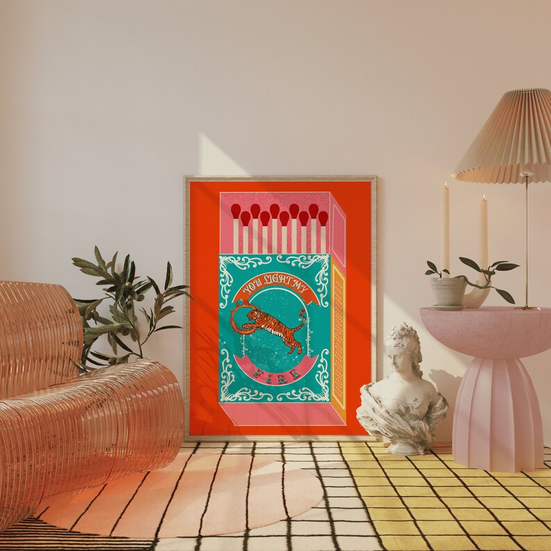 May include: A vintage-style illustration of a matchbox with a tiger jumping through a ring of fire. The matchbox is red, pink, and blue with the text "You light my fire" on the front.