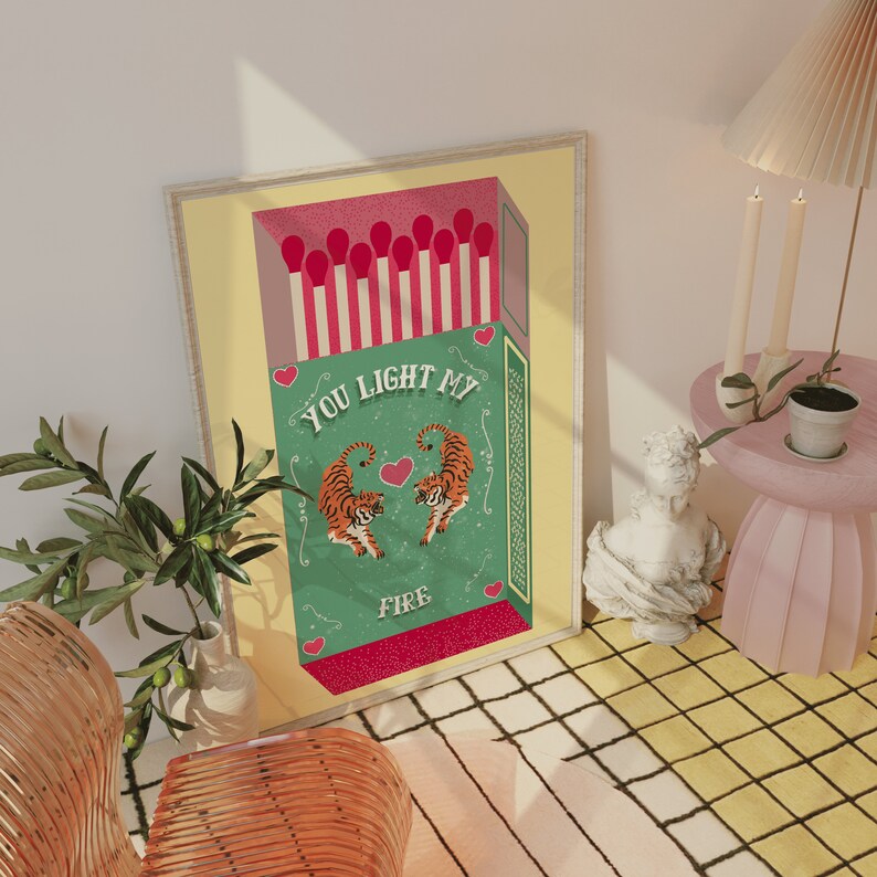 May include: A yellow and green illustration of a matchbox with red matchsticks and two tigers. The text on the matchbox reads "You Light My Fire".