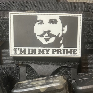 May include: A white patch with a black silhouette of a man's face and the text "I'M IN MY PRIME" in black.