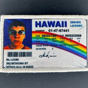 May include: A white and blue Hawaii driving licence with a rainbow border. The licence number is 01-47-87441. The licence is for Mc Lovin, 892 Momona St, Honolulu, HI 96820. The licence was issued on 06/10/1998 and expires on 06/03/2008.