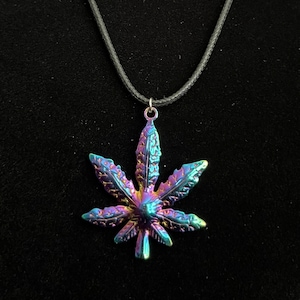 May include: A black cord necklace with a iridescent silver marijuana leaf pendant.