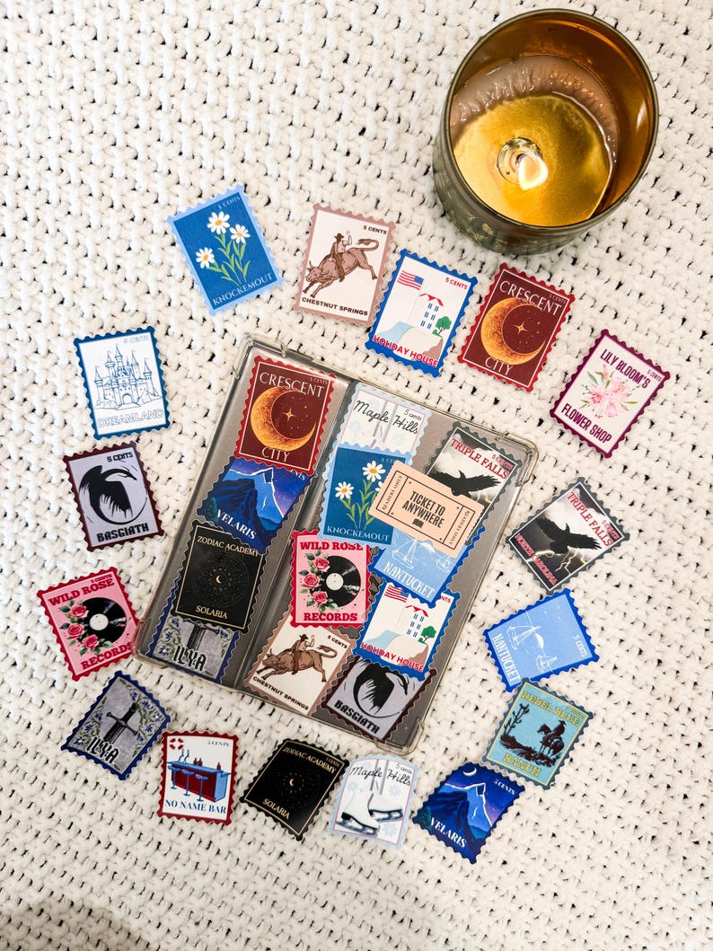 May include: A collection of colourful vintage-style postage stamp stickers featuring various designs, including a castle, a flower shop, a record store, a bar, a city skyline, a wild rose, a zodiac academy, a rocket ship, a horse rider, a mountain range, and a pair of ice skates. The stickers are arranged on a white crocheted surface.