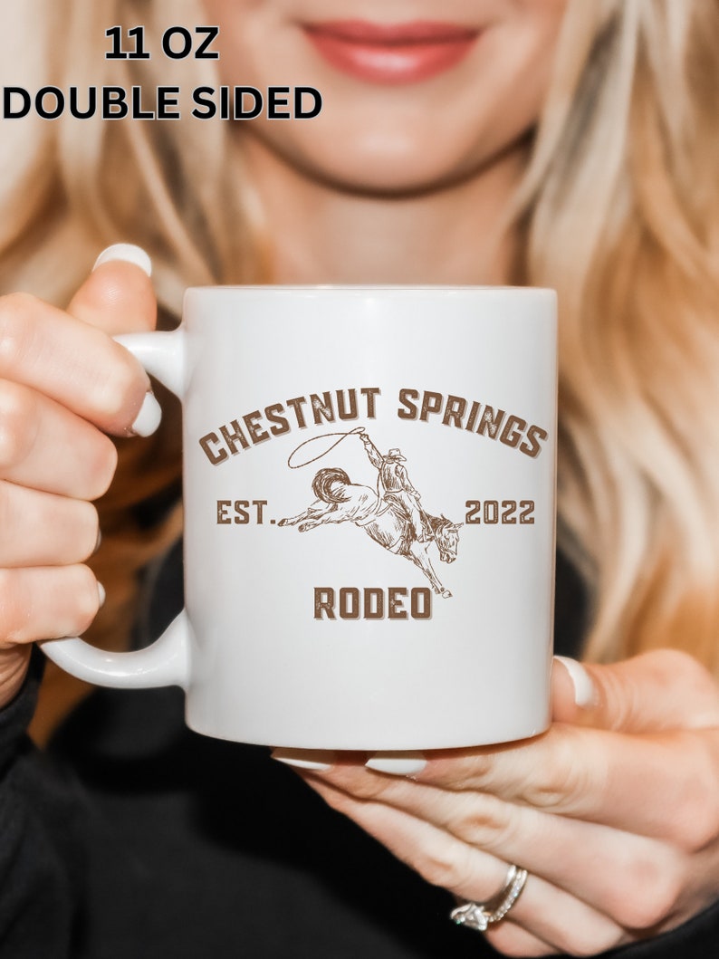 May include: White ceramic mug with a brown graphic of a cowboy riding a bucking horse. The text "Chestnut Springs Est. 2022 Rodeo" is printed on the mug.