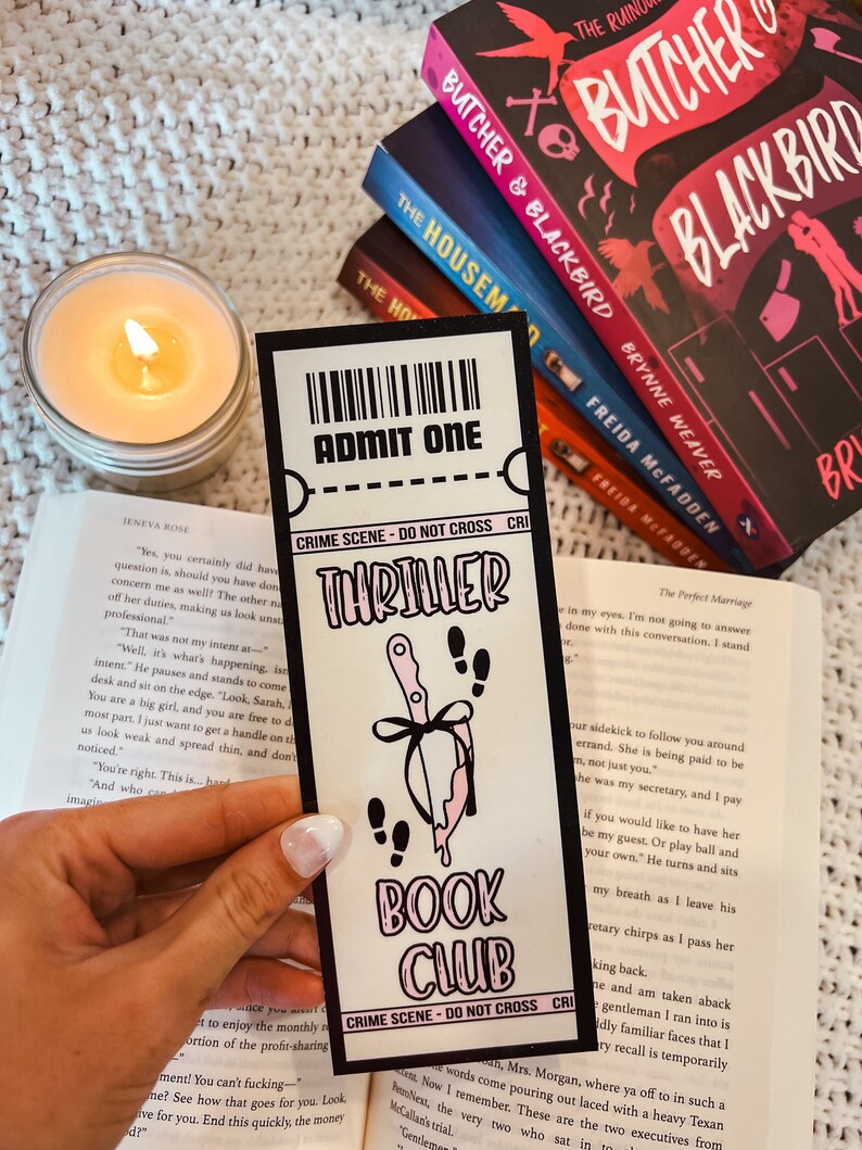 Może przedstawiać: Zakładka w kolorze r&oacute;żowym i czarnym z nożem i kapiącą krwią. Zakładka zawiera napis "Thriller Book Club" i "Crime Scene - Do Not Cross".