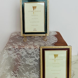 May include: Two decorative photo frames with gold-colored trim and ornate detailing. One frame has a dark green interior, the other a burgundy interior. Both frames feature the word "CONNOISSEUR" and are sized 5x7 inches (13x18cm).