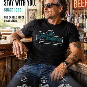 May include: Black t-shirt with "Double Deuce" graphic, worn by a person wearing sunglasses. The shirt has a teal and white design with text that reads "Since 1989 Live Music Jasper, Missouri." The image also includes text that says "Wear the Legend."