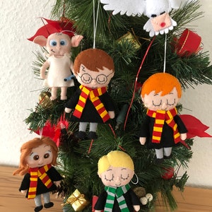 以下が含まれることがあります： ハリーポッターシリーズのキャラクターをフィーチャーしたフェルト製のクリスマスオーナメントのセット。オーナメントには、ハリーポッター、ロン・ウィーズリー、ハーマイオニー・グレンジャー、ドラコ・マルフォイ、そしてヘドウィグのフクロウが含まれています。オーナメントはすべてホグワーツの制服を着ており、クリスマスツリーの背景があります。
