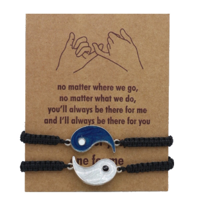 May include: Two black friendship bracelets with a yin yang charm on each. The charms are silver with blue and white enamel. The card reads: "no matter where we go, no matter what we do, you'll always be there for me and I'll always be there for you".