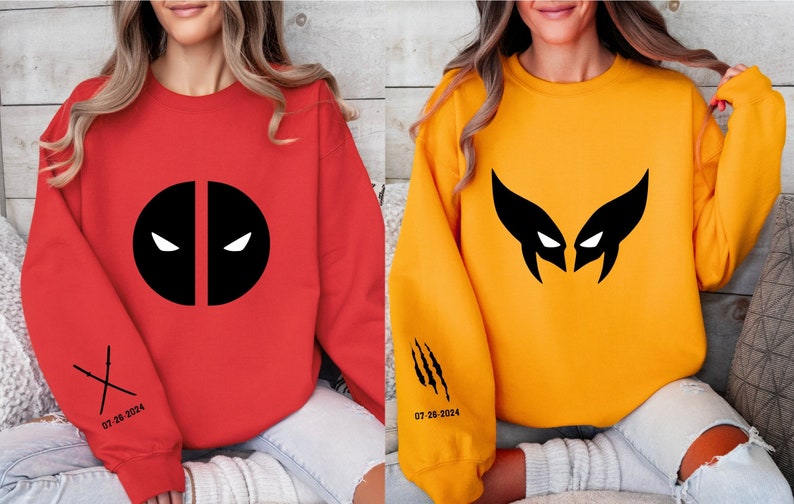 May include: Two sweatshirts, one red and one yellow, with black superhero logos. The red sweatshirt features a Deadpool logo, while the yellow sweatshirt has a Wolverine logo. Both sweatshirts have a date printed on the sleeve.