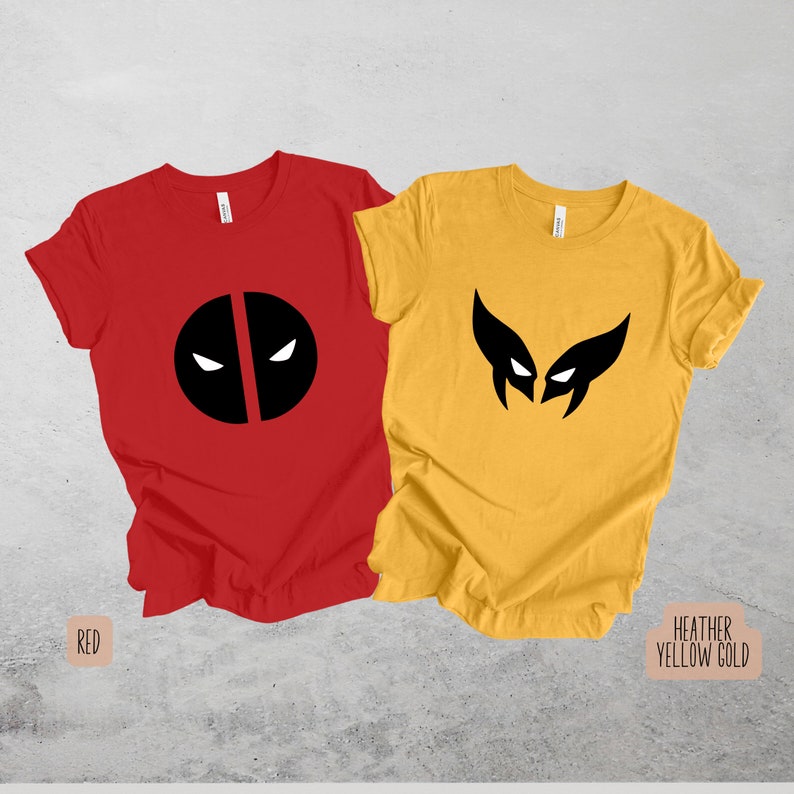 May include: Two t-shirts with superhero logos. The red shirt has a black Deadpool logo and the yellow shirt has a black Wolverine logo. The text "RED" is below the red shirt and the text "HEATHER YELLOW GOLD" is below the yellow shirt.