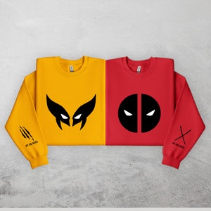 May include: Two sweatshirts, one yellow and one red, with black graphic prints of Wolverine and Deadpool. The yellow sweatshirt has claw marks on the sleeve and the text "07-28-2024". The red sweatshirt has crossed swords on the sleeve and the text "07-28-2024".