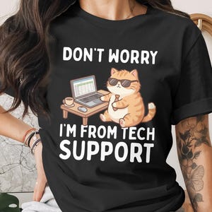 Könnte beinhalten: Schwarzes T-Shirt mit dem Text "DON'T WORRY I'M FROM TECH SUPPORT". Die Grafik zeigt eine Cartoon-Katze mit Sonnenbrille und Krawatte, die vor einem Laptop sitzt, mit einer Kaffeetasse auf einem kleinen Tisch.